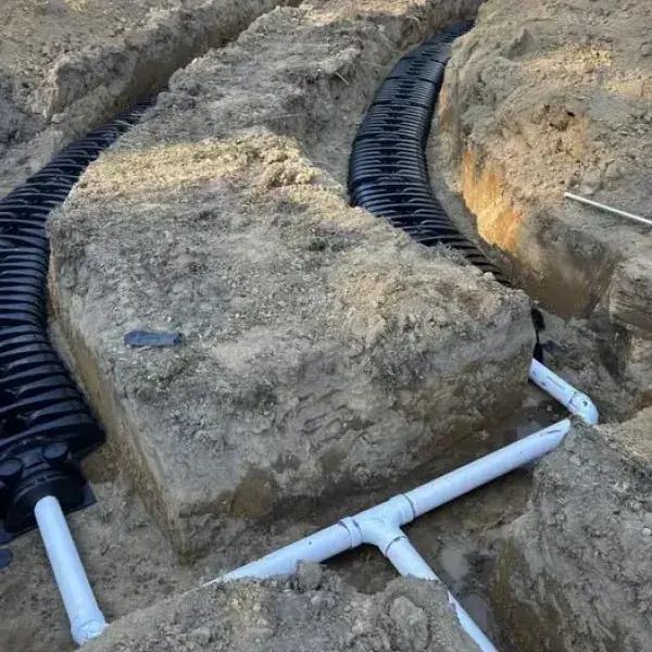 Two curved chamber drain field lines fed by a white PVC tee between the trenches