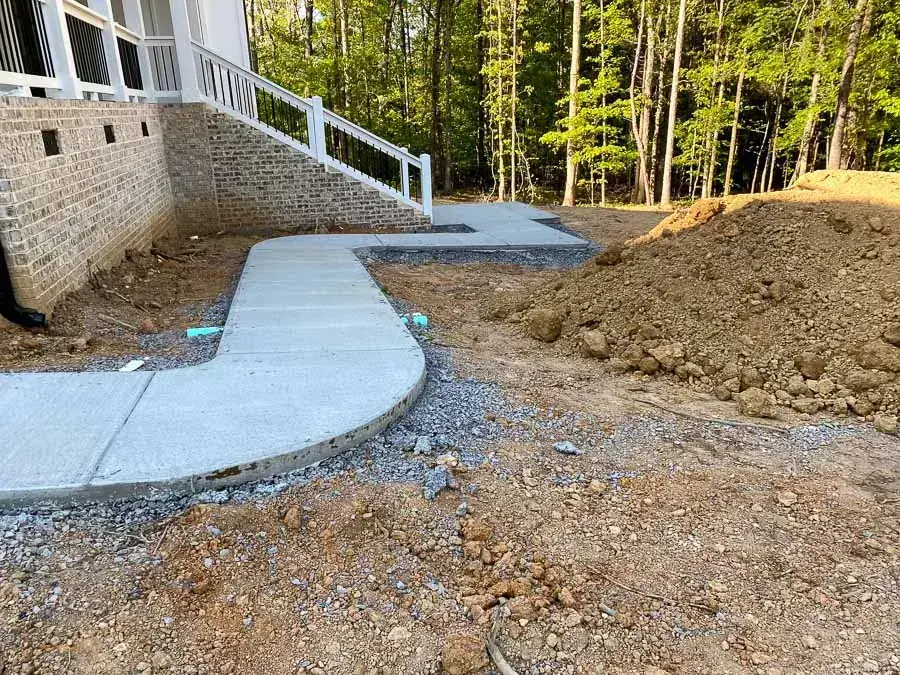 New house with a fresh concrete walkway and gravel, grading finished and the septic area still to be landscaped New house with a fresh concrete walkway and gravel, grading finished and the septic area still to be landscaped