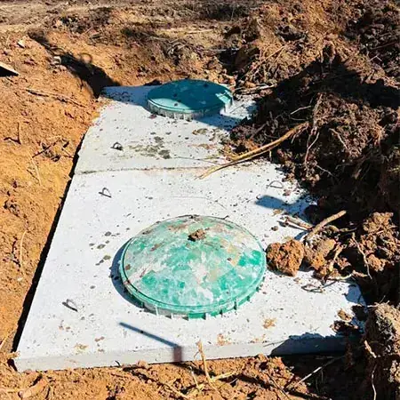 Top of a precast concrete septic tank with two green access lids showing